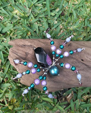 Load image into Gallery viewer, Beaded spider decoration on a piece of wood with grass in the background
